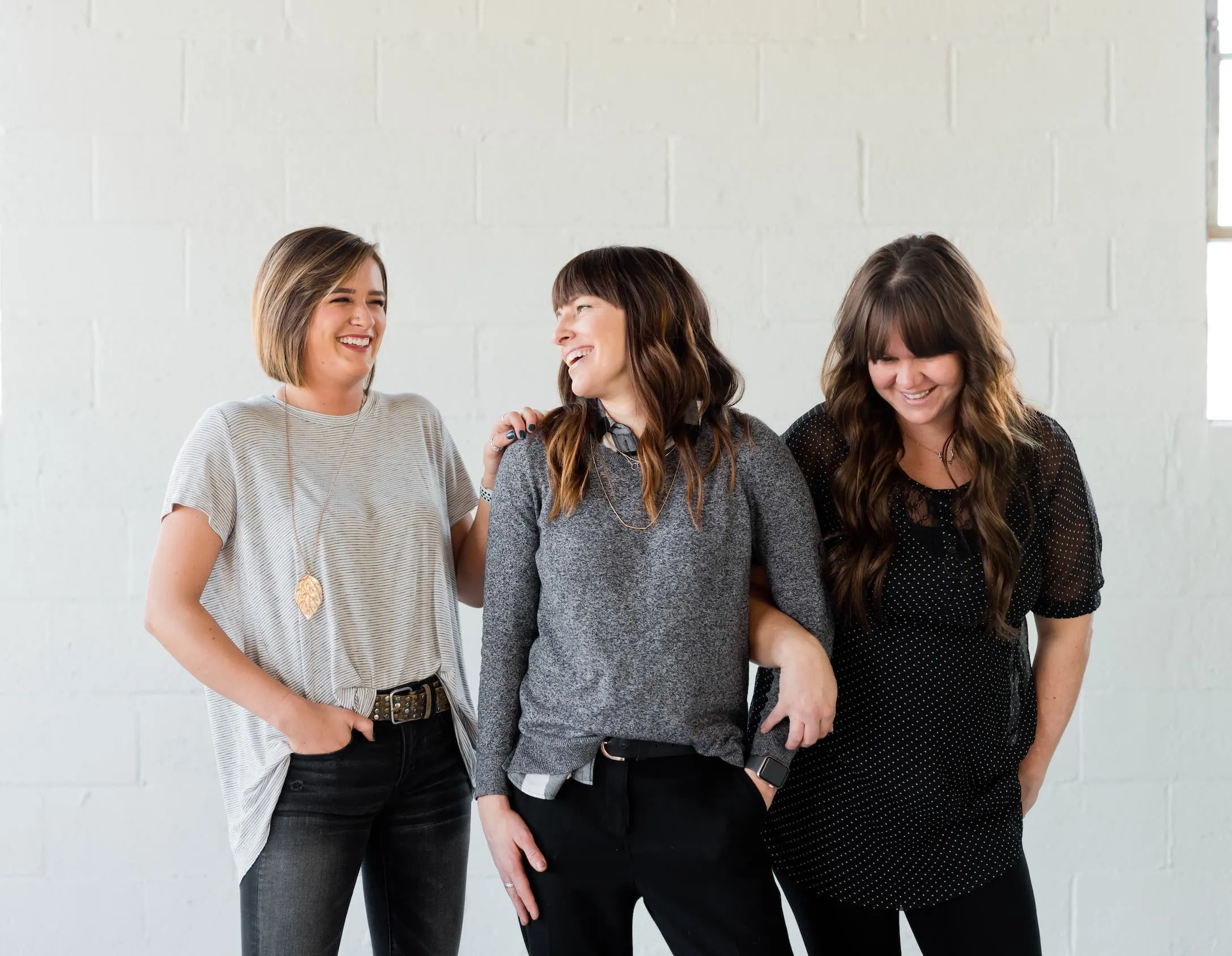 Three professional women standing together laughing.