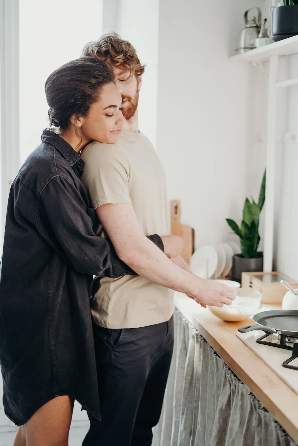 A strong relationship example showing a couple standing in the kitchen cooking together. An example of a happy relationship.