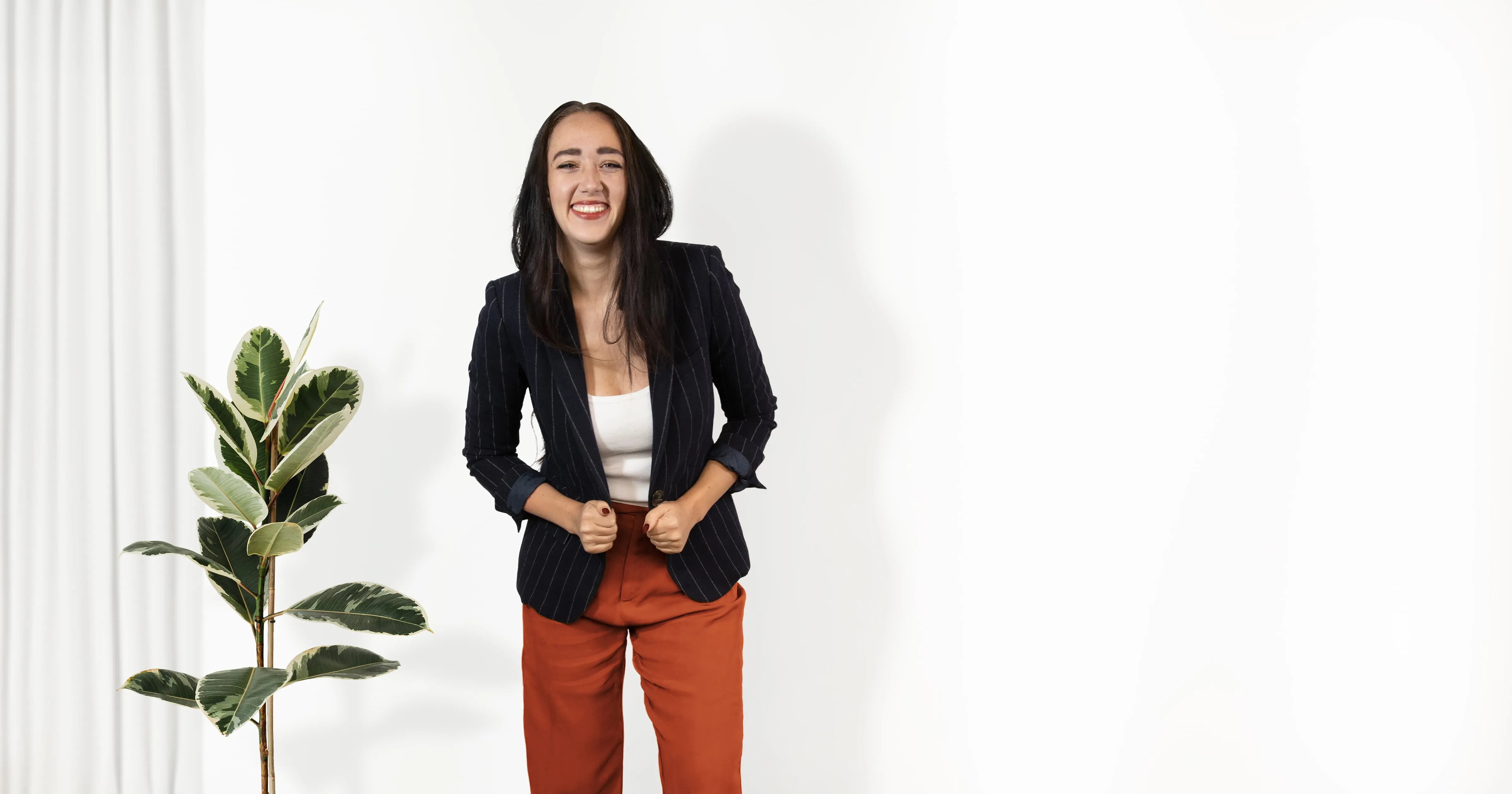 Zoe West, life and relationship coach, standing next to a tall plant laughing.