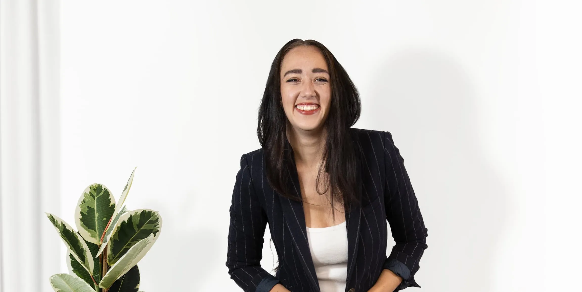Zoe West, life and relationship coach based in Melbourne, standing next to a tall plant laughing.